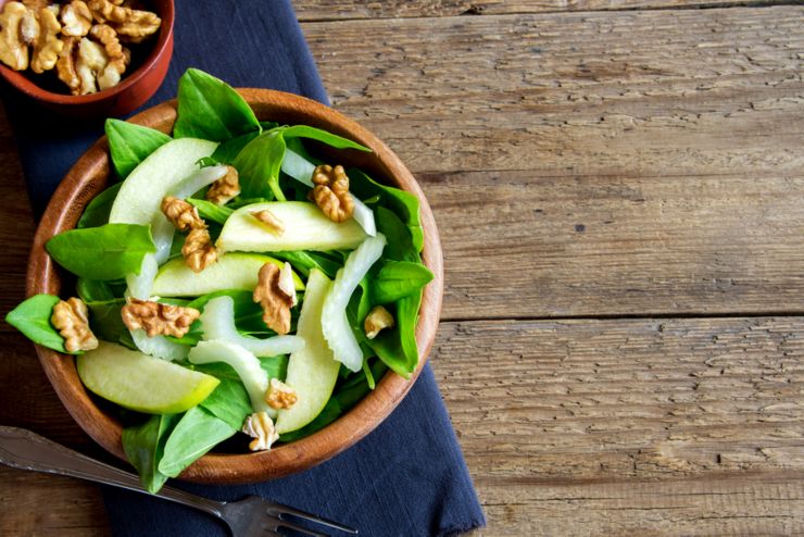 Waldorf salad with green apple celery and walnuts in wooden bowl over rustic background with copy space