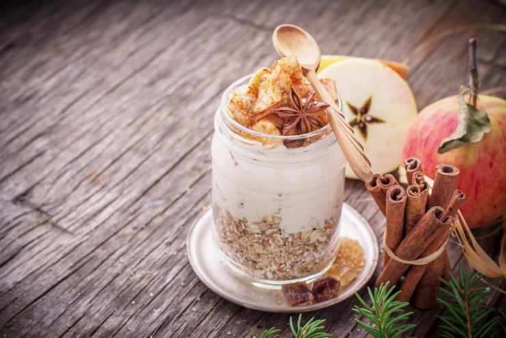 Overnight Oatmeal with yogurt, slices of fresh apples in the batch of ground cinnamon in a glass jar on a wooden background with apples, cinnamon sticks and honey. The concept of healthy natural foods. selective Focus