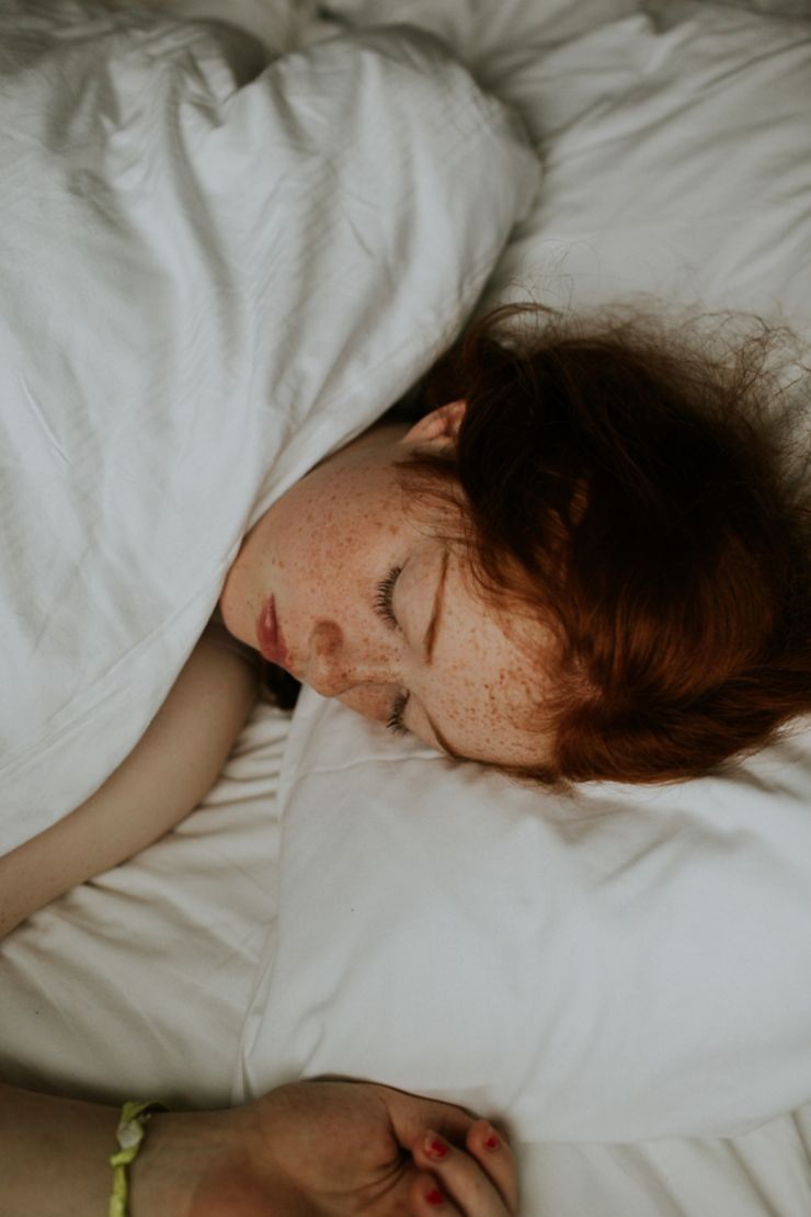 Portrait of a red-haired girl with freckles sleeping in her bed