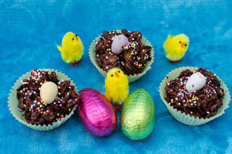 Looking down on a perfect Easter collection of Easter eggs chocolate cornflake cakes and little baby yellow toy chicks