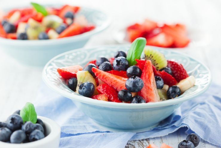 Summer salad with ripe fresh fruits and berries on white wooden background selective focus