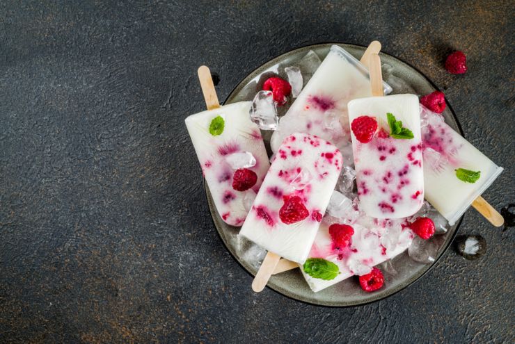 Summer sweet desserts, homemade organic ice cream popsicles from raspberry and yogurt, dark rusty background copy space top view