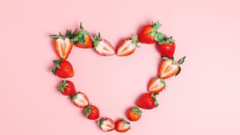 Frame in the shape of a heart made from ripe strawberries on a pink background. Beautiful background for the designer. Love concept. Valentine's day concept. border, flat lay, copy space.