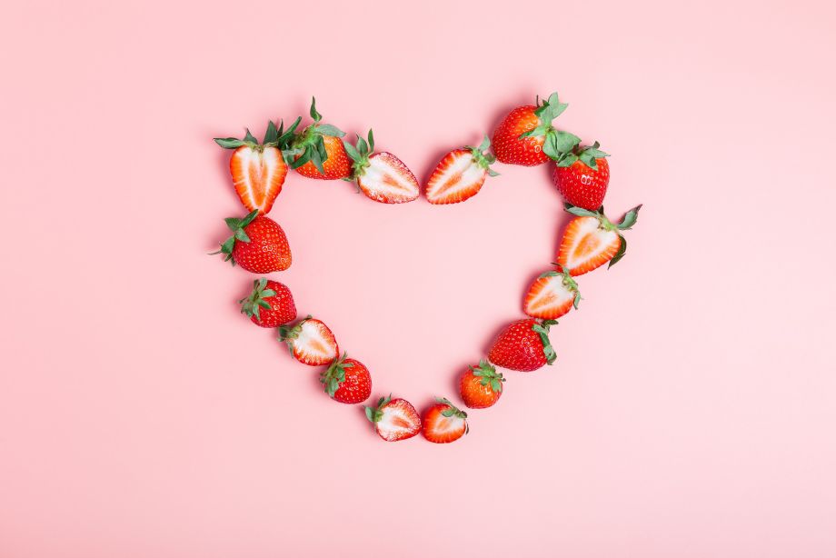 Frame in the shape of a heart made from ripe strawberries on a pink background. Beautiful background for the designer. Love concept. Valentine's day concept. border, flat lay, copy space.