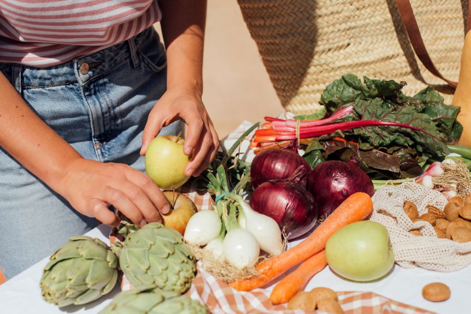 A woman emptying the basket with some vegetables and fruits from the organic garden.