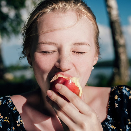 Woman eating apple during sunny day