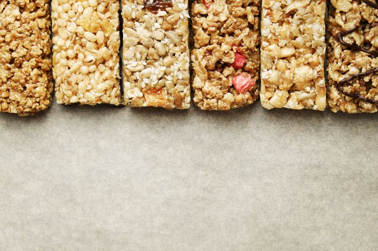 Bunch of mixed gluten free granola energy bars with dried fruit & various nuts, wooden background. Healthy vegan super food, different fitness diet snacks for sporty lifestyle. Top view, copy space.