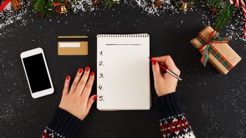 Christmas wish list writing. Woman creating present list for winter holidays. Top view, preparing for xmas and new year concept