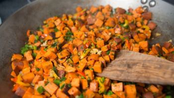 Sweet Potato Hash with Fresh Herbs, Peppers and Onions Cooking in Skillet