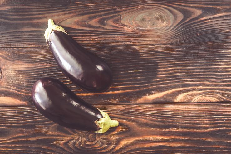 Two halves of aubergine on the wooden background: top view