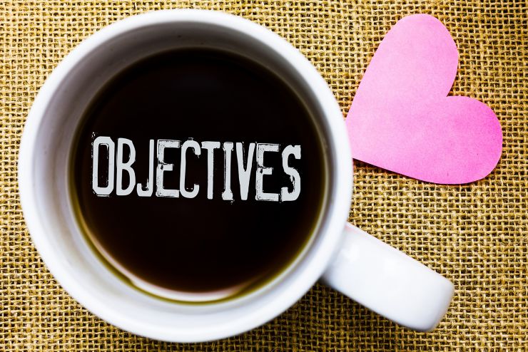 Text sign showing Objectives. Conceptual photo Goals planned to be achieved Desired targets Company missions Tea time coffee cup office typing work jute rough background love heart