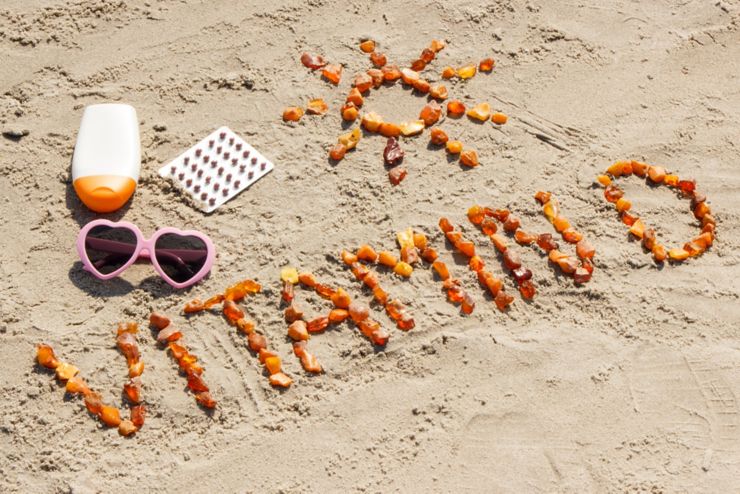 Medical pills, inscription vitamin D made of amber stones and accessories for sunbathing at beach, concept of vacation time and prevention of vitamin D deficiency