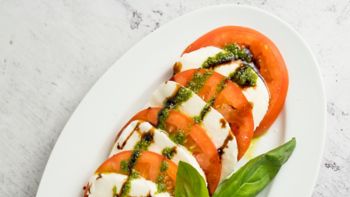 caprese with tomato slices and herbs served with pesto, Italian caprese with tomato, herbs and pesto